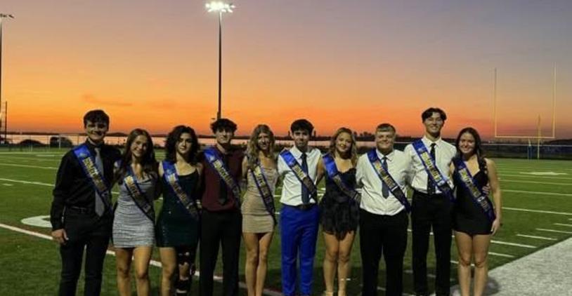 Group of teenagers dressed up for an event in front of a sunset on a football field.