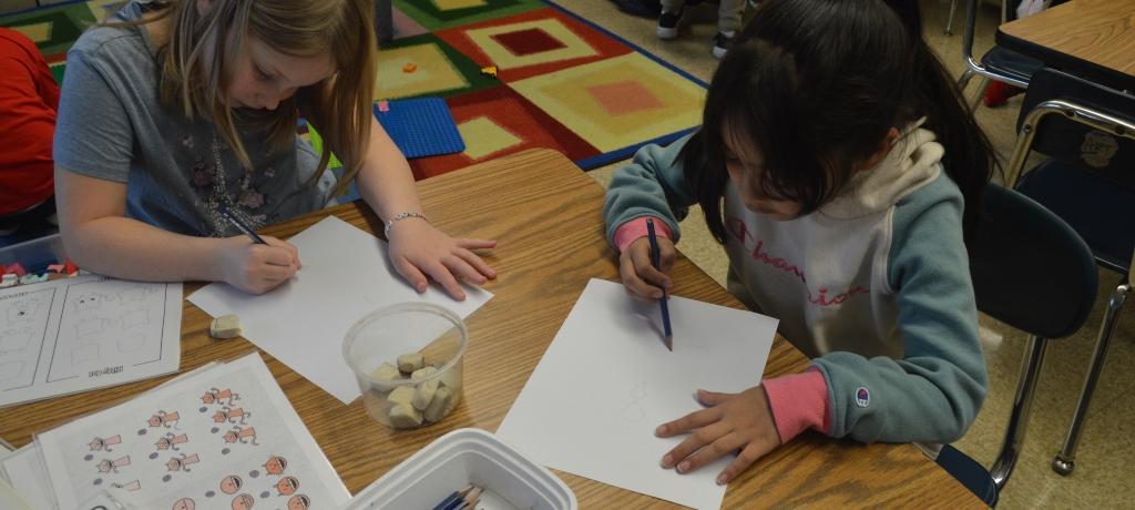 two girls draw with pencils