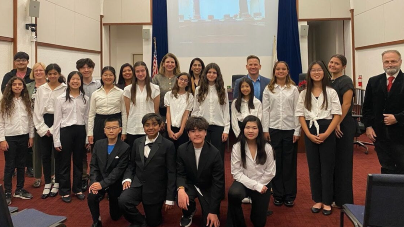 Photo of student choir members, their director, and board members posing for a photo