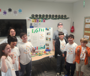 Robotics Club students and coach standing around posterboard presentation of Easter Island