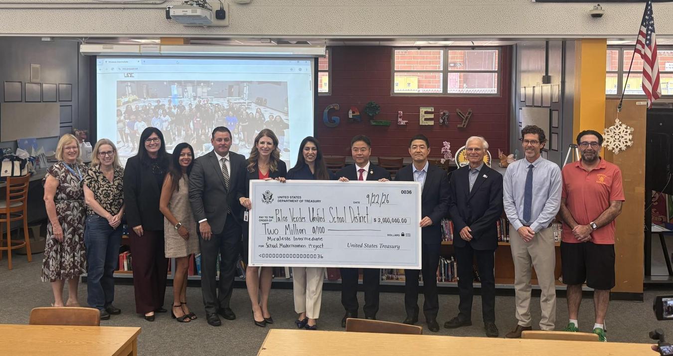 A group of people, including a man in a suit and a large check presentation.