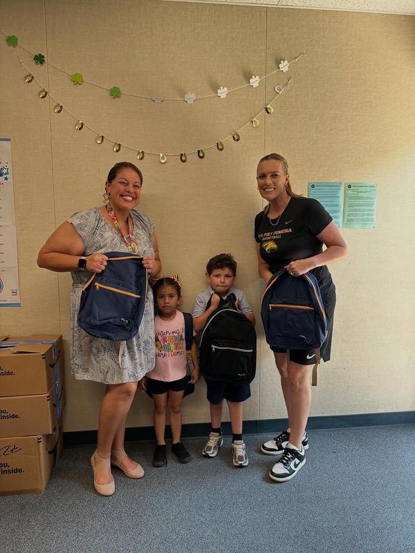 four persons 2 adults and 2 children holding backpacks