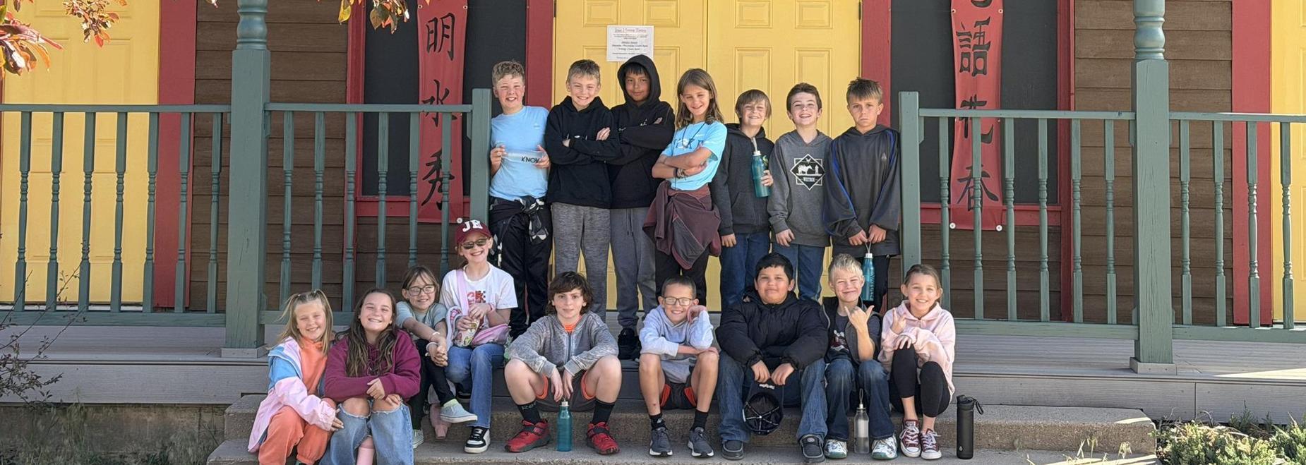 Group of children posing in front of a building with vibrant red and yellow doors.