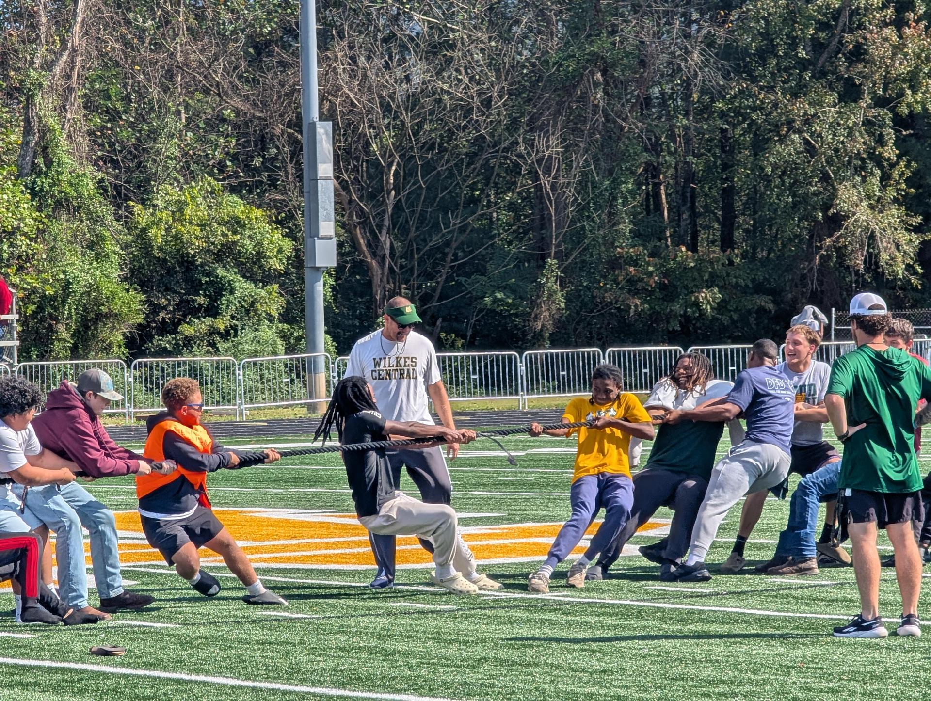 Participants competing in a tug-of-war on a green field.