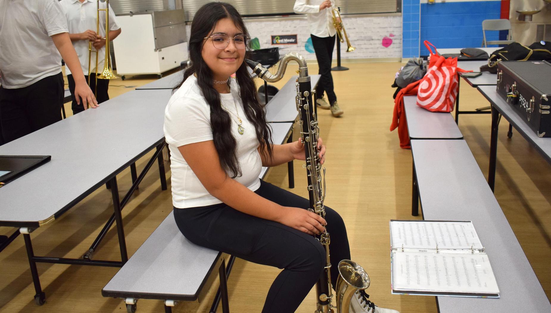 Female student sitting with a clarinet and sheet music in a school.