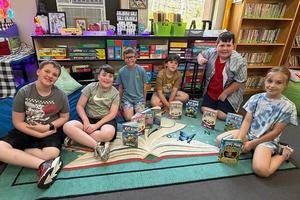 6 students are seated on the floor with many books sitting among them by the livestream authors