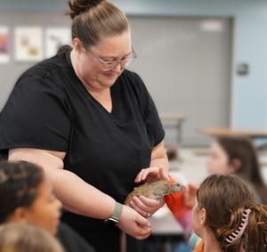 A member from South Kent Veterinary office lets students pet an animal.
