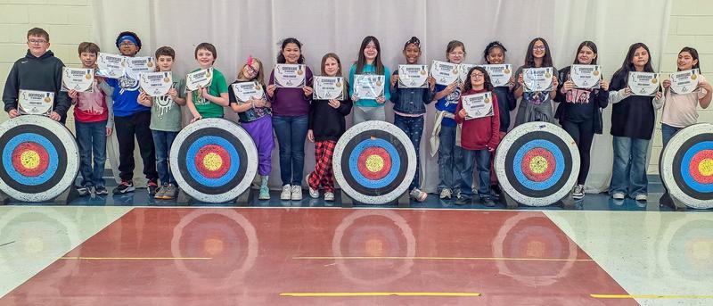 A group of archery students in a gym
