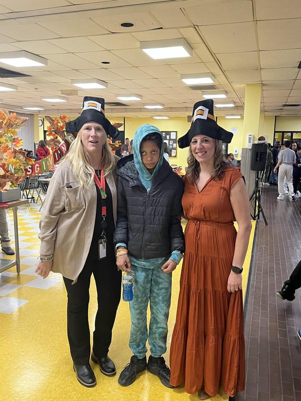 Student with two staff members, both wearing pilgrim hats