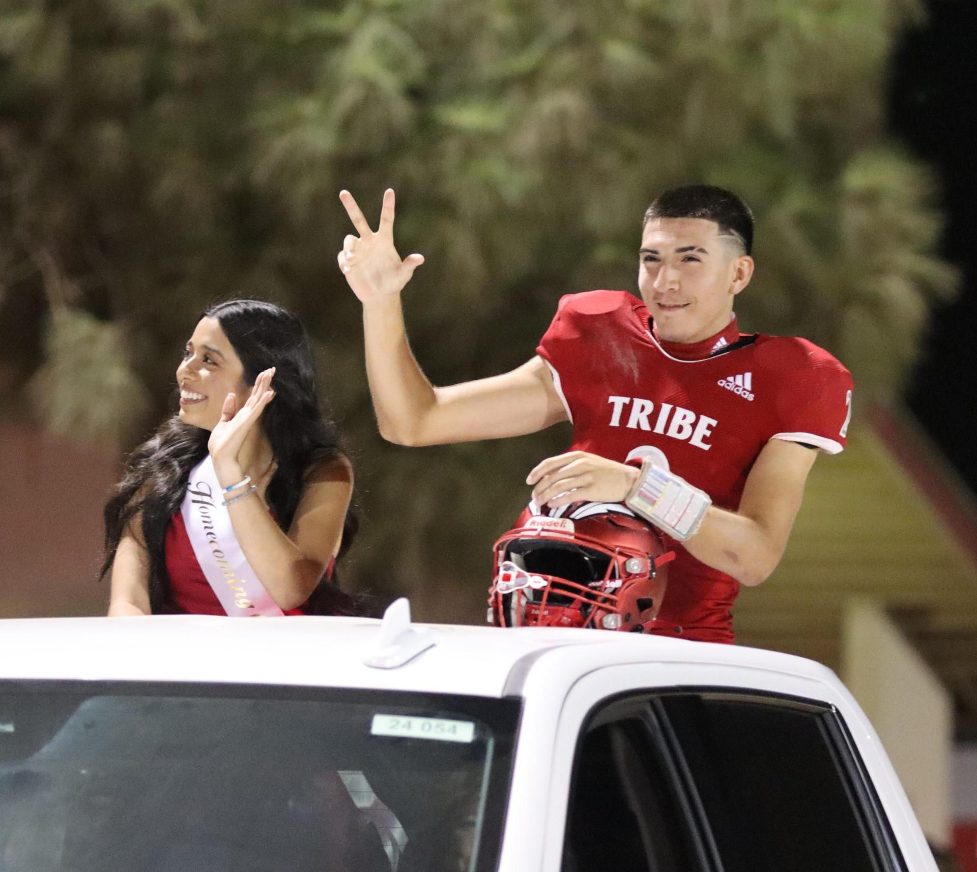 homecoming king and queen candidates entering the stadium in trucks