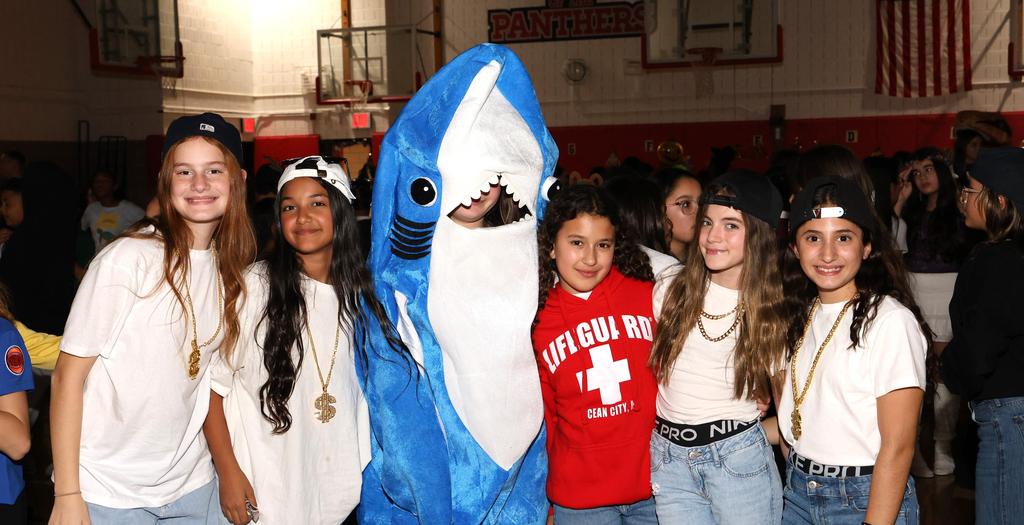 1 person dressed as a shark and 4 girls dressed with white t-shirts and jeans.