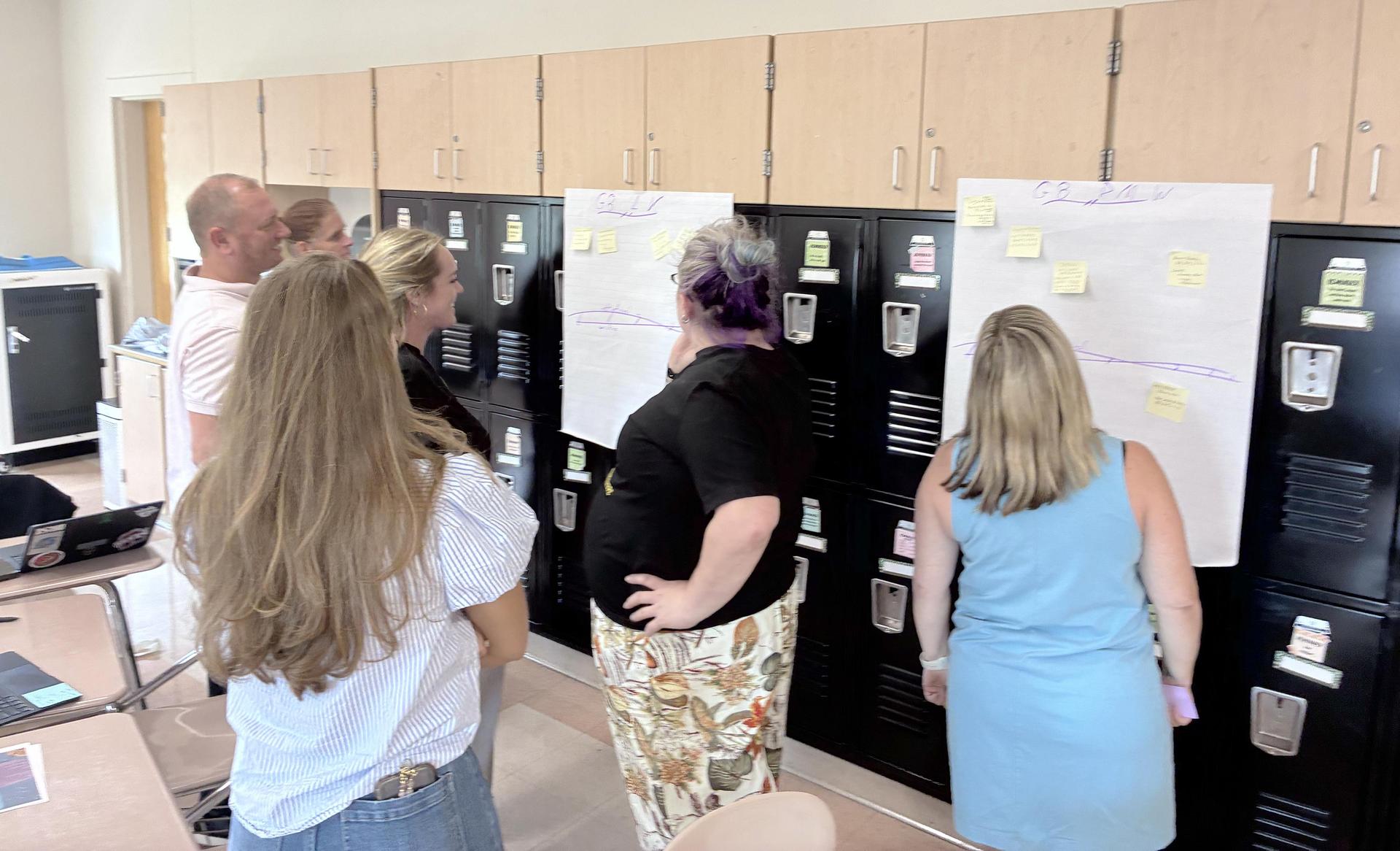 A group of people collaborating around sticky notes on a wall of lockers.