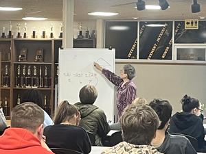 Math instructor points to information on white board