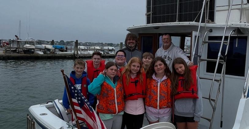 Group of kids wearing life jackets on a boat near the marina.