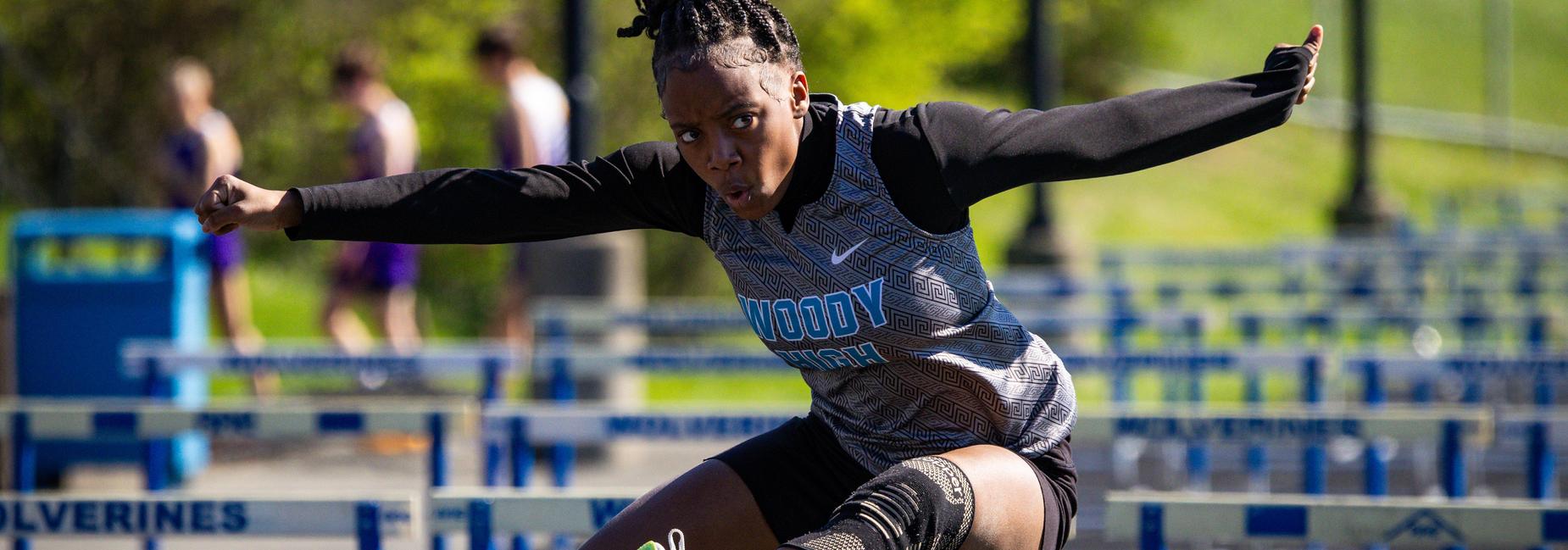 A track athlete clears a hurdle