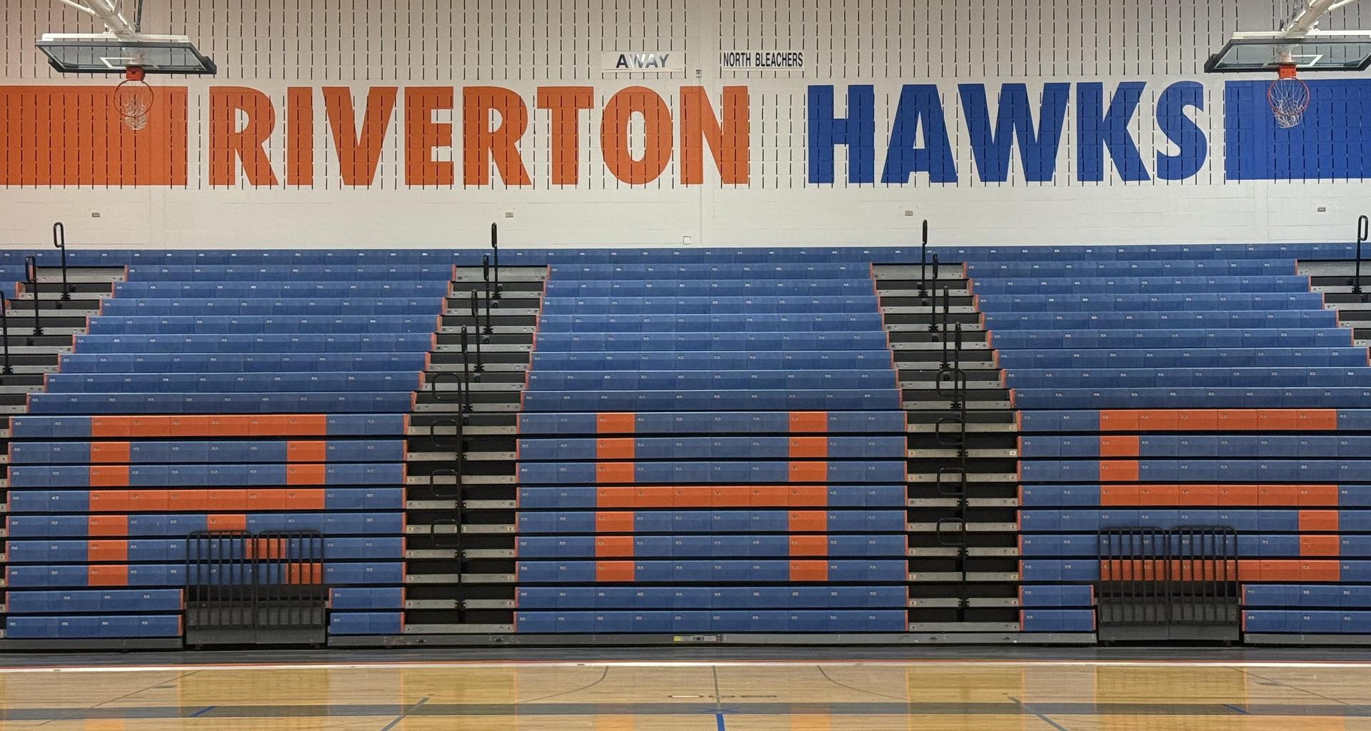 Bleachers with orange and blue colors, displaying 'Riverton Hawks' and 'RHS.'