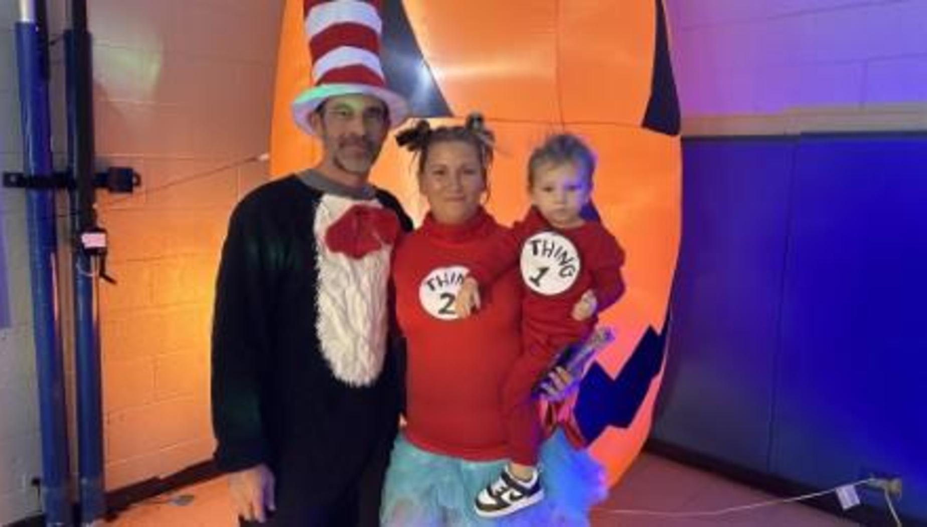 Family dressed in Halloween costumes, with one as the Cat in the Hat and two as Thing 1 and Thing 2.