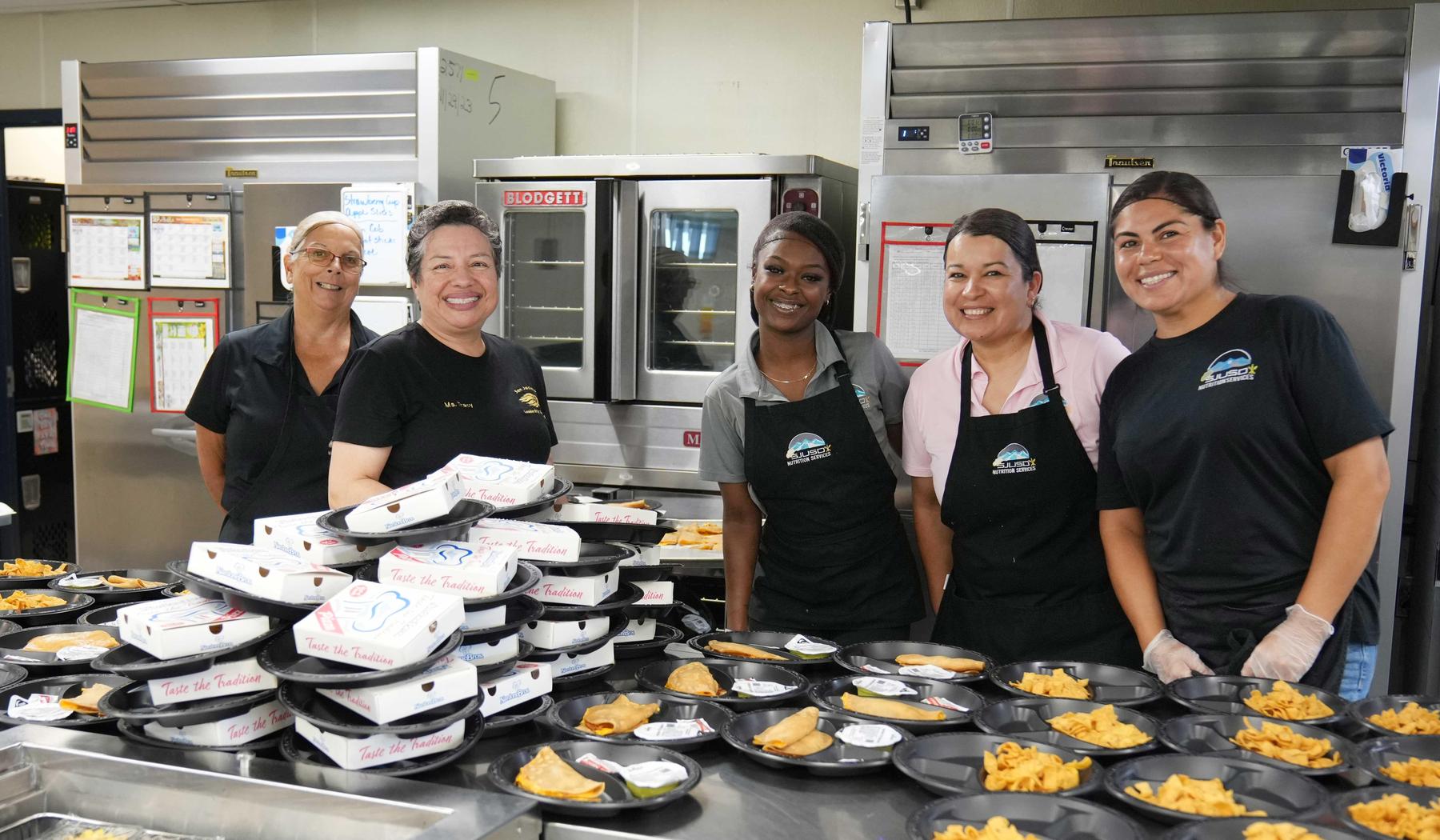 Five nutrition service staff with meals ready for students