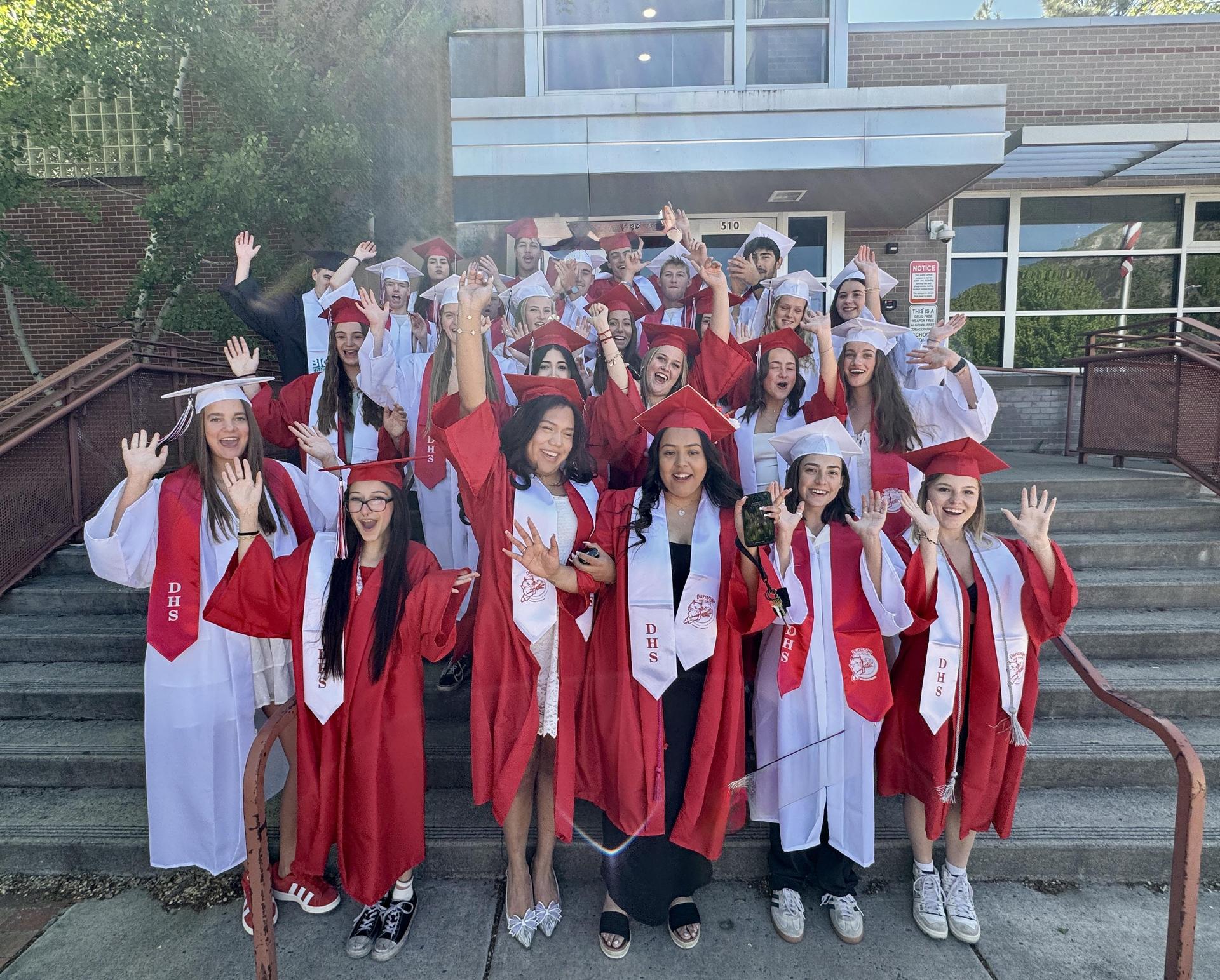 Graduates in caps and gowns cheer in a group