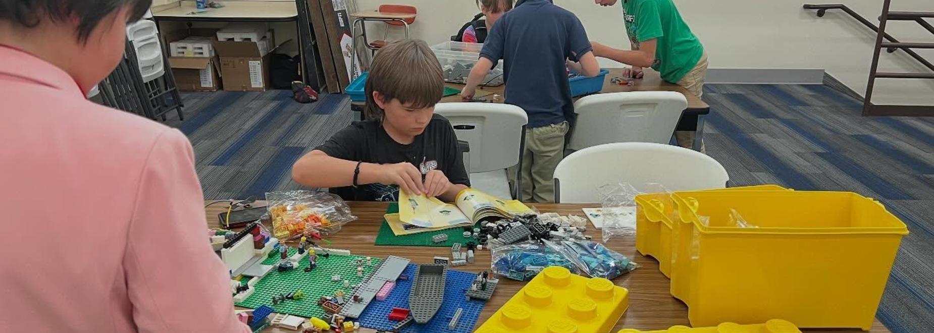 Children engaging in a Lego building activity with various sets and pieces on a table.
