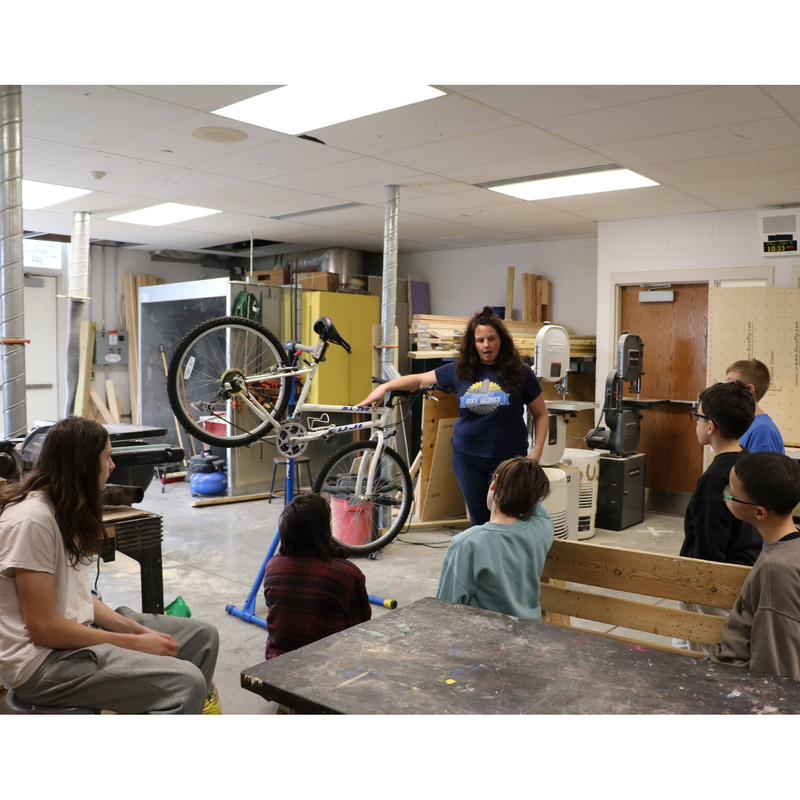 instructor showing a group of students the parts of a bicycle