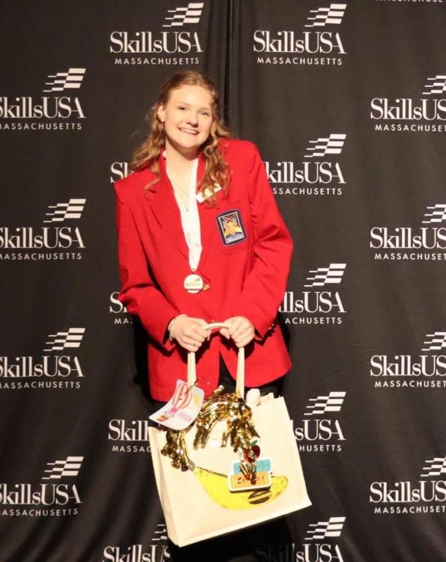 A girl in a red blazer holding a tote bag with gold tinsel.
