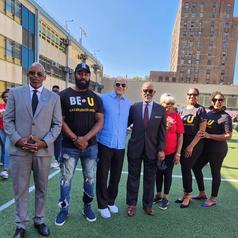 Group of people in formal attire and casual shirts posing outdoors.
