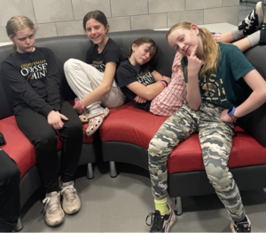 A team of elementary students posing on a couch A team of elementary students in red headbands posing with certificates at the Odyssey of the Mind competition.