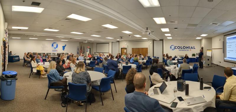 wide shot of adults sitting at round conference tables