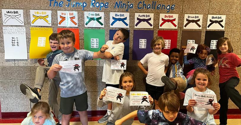 Kids posing with certificates in front of a wall display of colored belts.