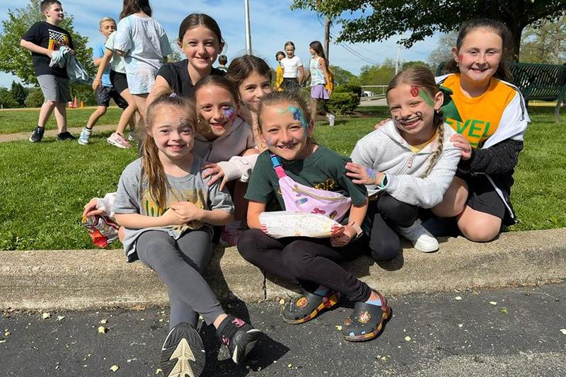 Level Green Third Graders Charlotte Teoli, Gemma Armbrust, Ruby Mortimore, Aubrey Divens, Ryann Dulemba, Clara Briscoe, and Paisley Hitchen sit down on the curb to take a break from the day’s activities
