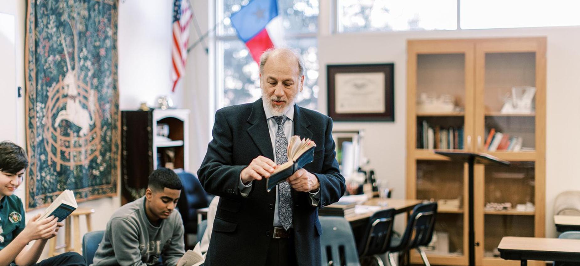 Teacher holds a book while leading a high school class