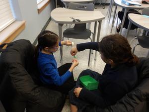 Two girls tape their box together.