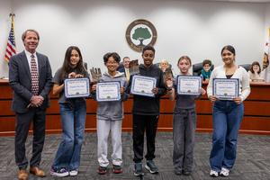 Walt Disney Elementary students posing together with certificates during the February 2026 board meeting presentation