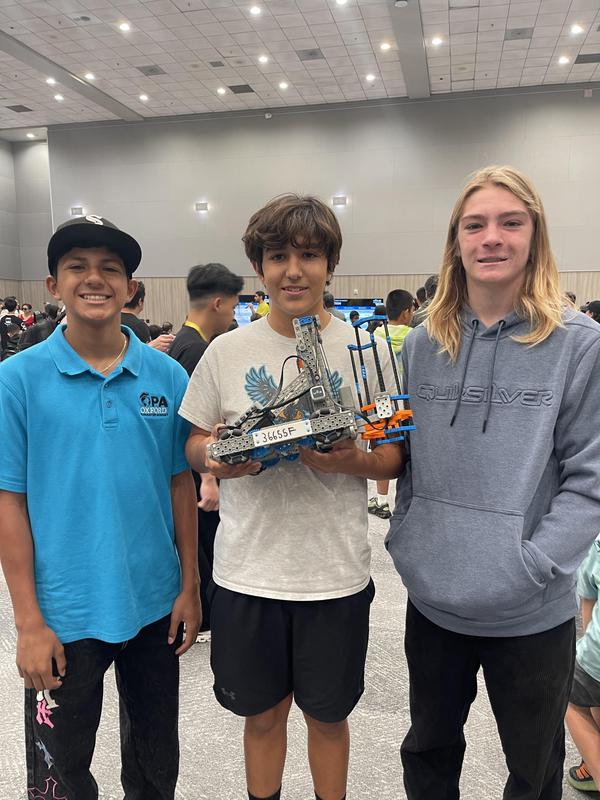 3 kids competing and holding their robot