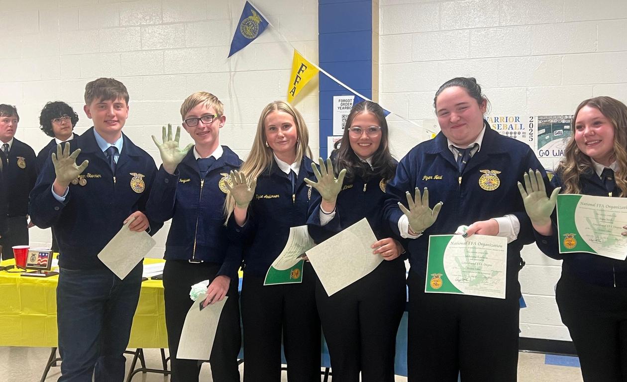 Group of students proudly displaying their hands and certificates at an event.