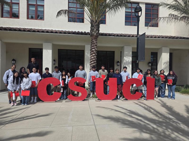 Group of students posing in front of large CSUCI letters with palm trees.