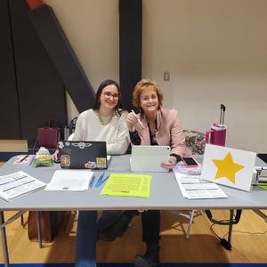 Two PUSD staff members smile at a registration table during the Kinder Round-Up event.
