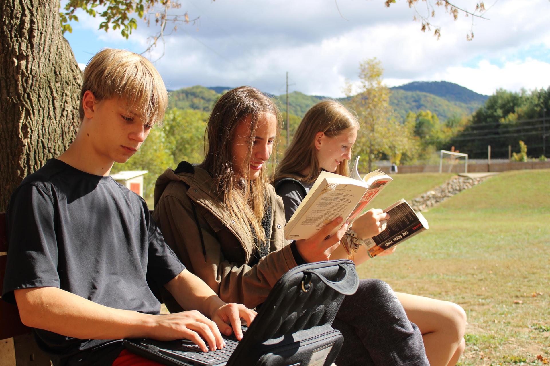 Students sitting on a bench outdoors, reading