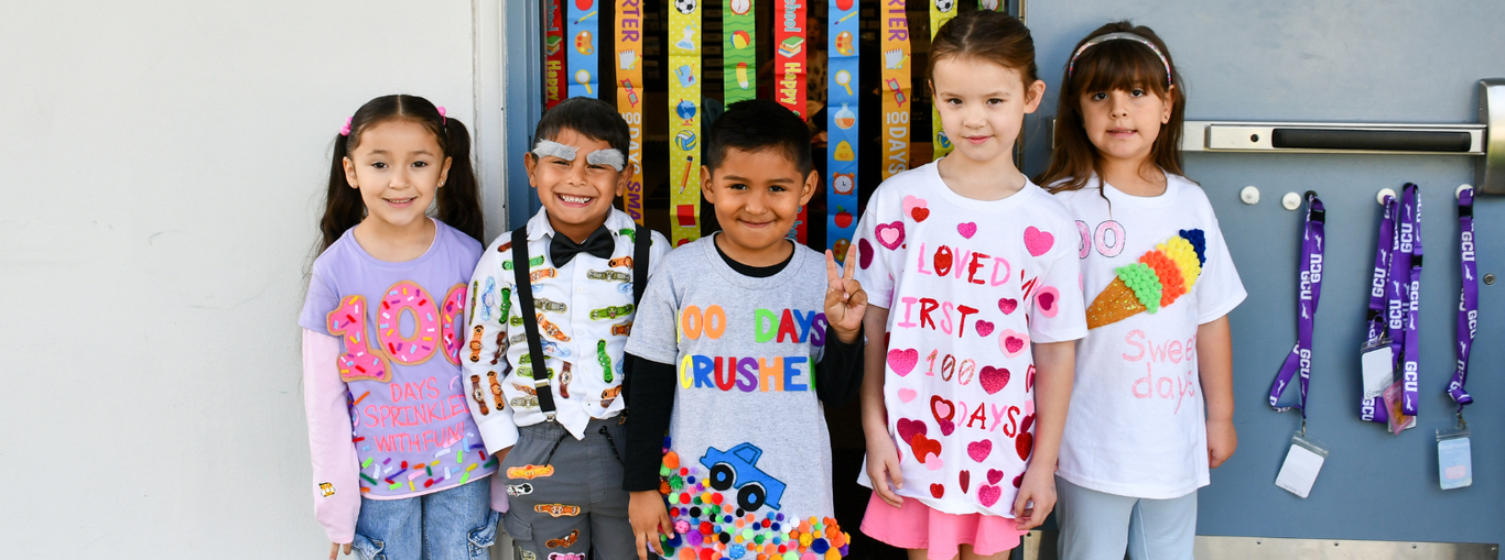 Five children in festive outfits, showing off shirts decorated for a special celebration.