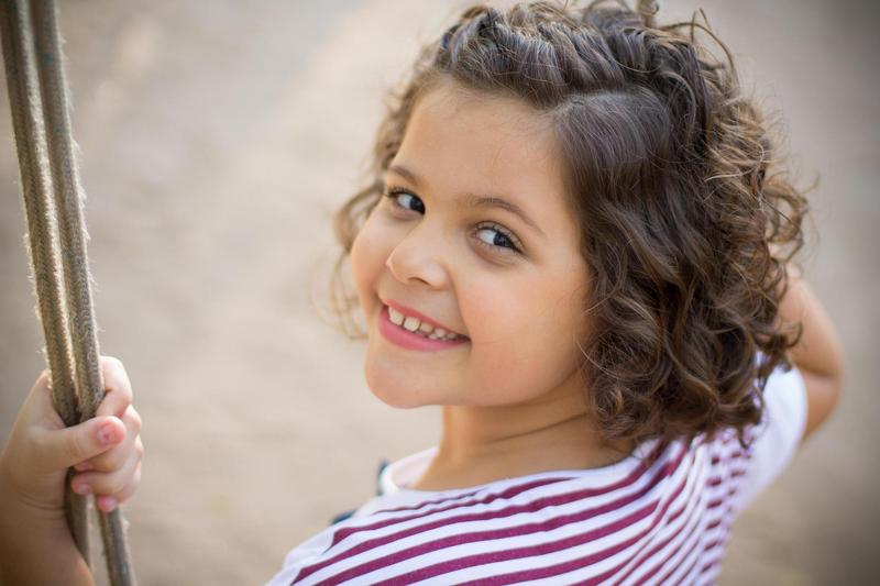 A smiling child on a swing looks over her shoulder