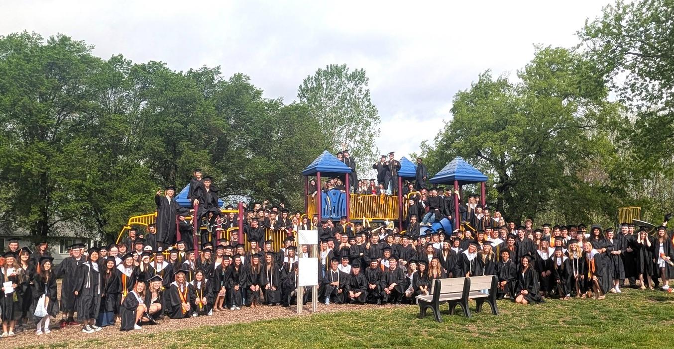 Large group of graduates posing together on a playground.