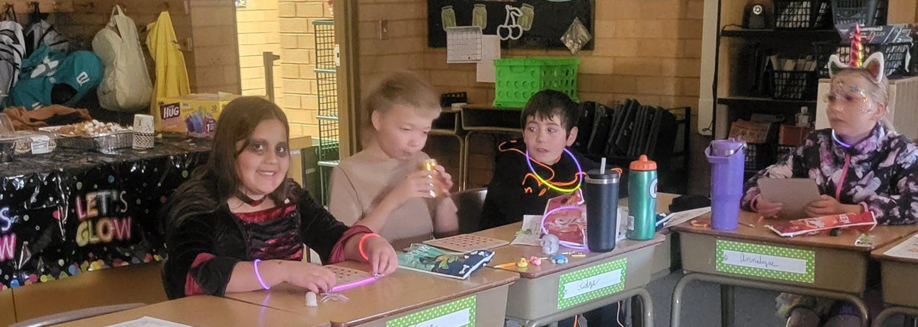 Students seated at desks with name tags, hands working on crafts and projects.