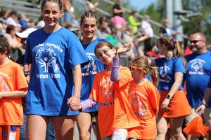 A Penn Yan student-athlete waves while walking hand-in-hand with a student volunteer.