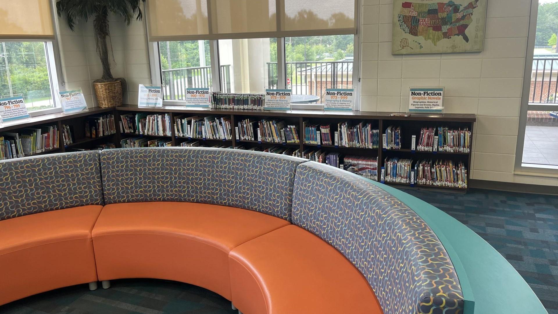 Cozy library corner with curved seating and bookshelves filled with children's books.