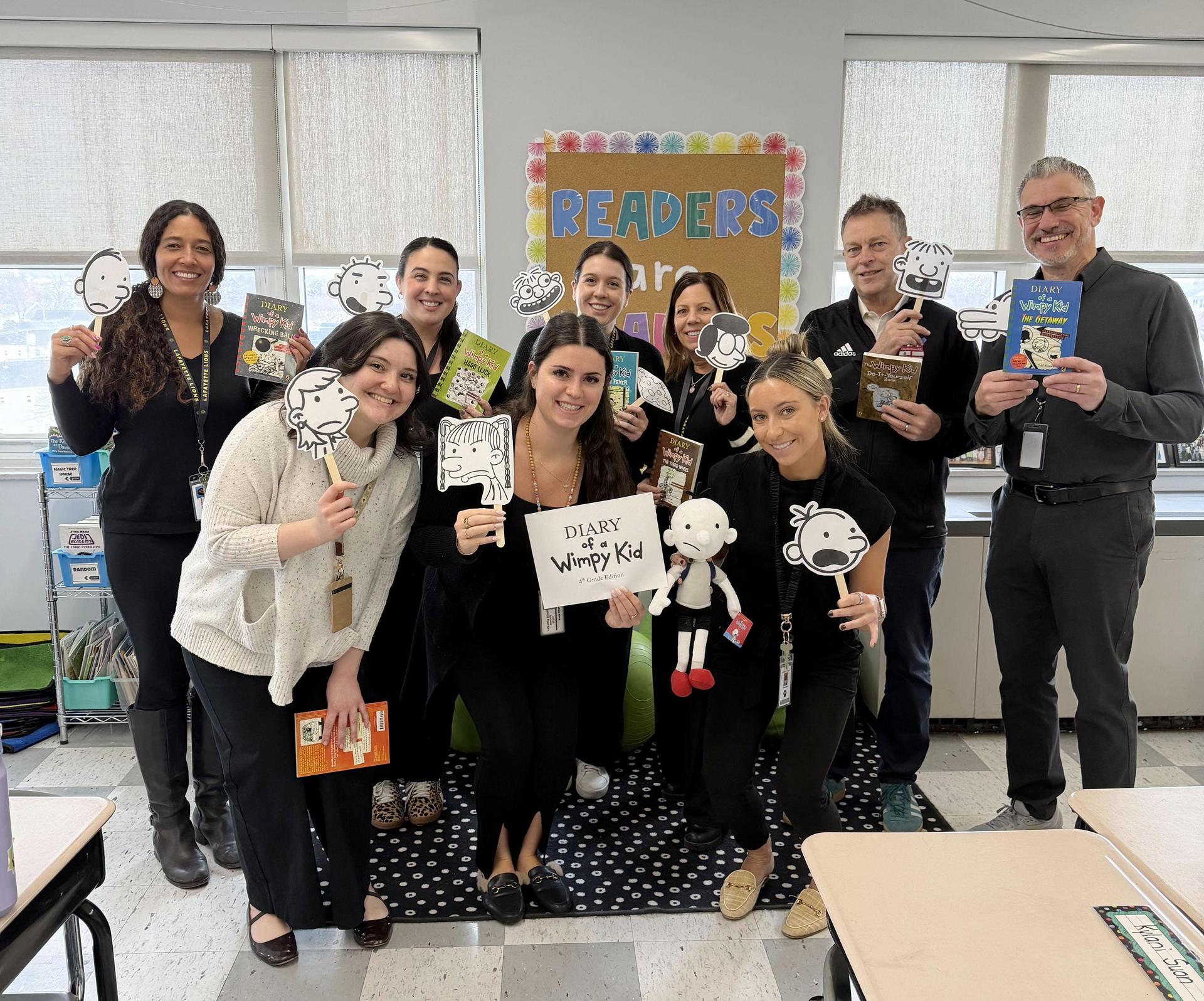 Group of educators posing with books and character props from a children's series.