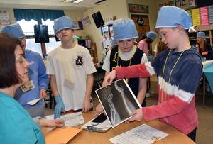 Students examine an X-ray with a teacher in a classroom setting.