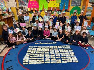The kindergarten students pose in front of the money they collected for the 100th day of school!