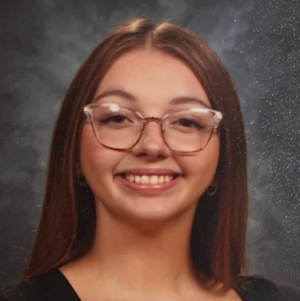 woman smiling at camera with straight hair wearing glasses