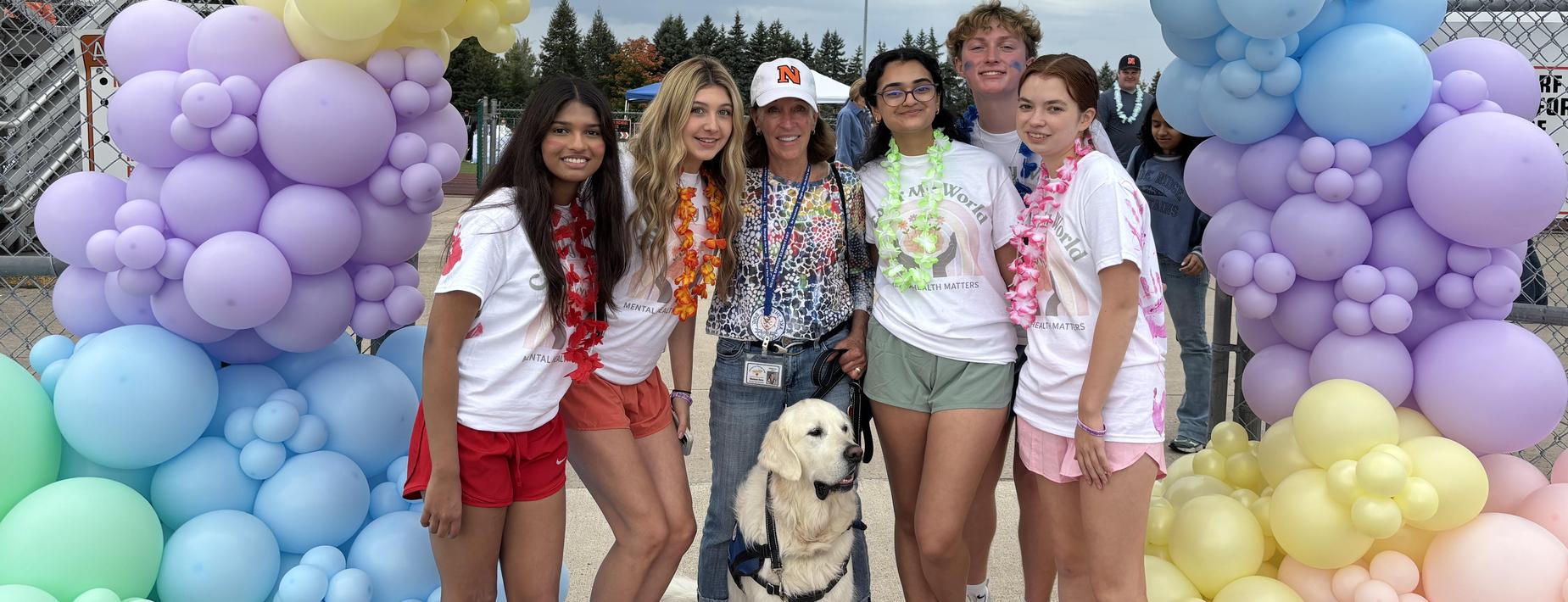Students standing under a colorful balloon arch.